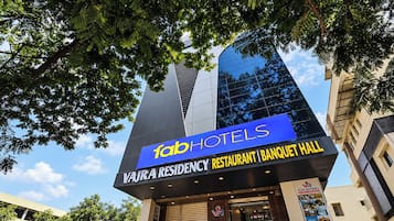 Un edificio con un letrero que dice 'fab hotels' y 'Vajra Residency Restaurant | Salón de banquetes'.