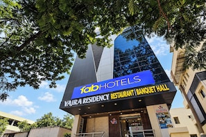 Un edificio con un letrero que dice 'fab hotels' y 'Vajra Residency Restaurant | Salón de banquetes'.