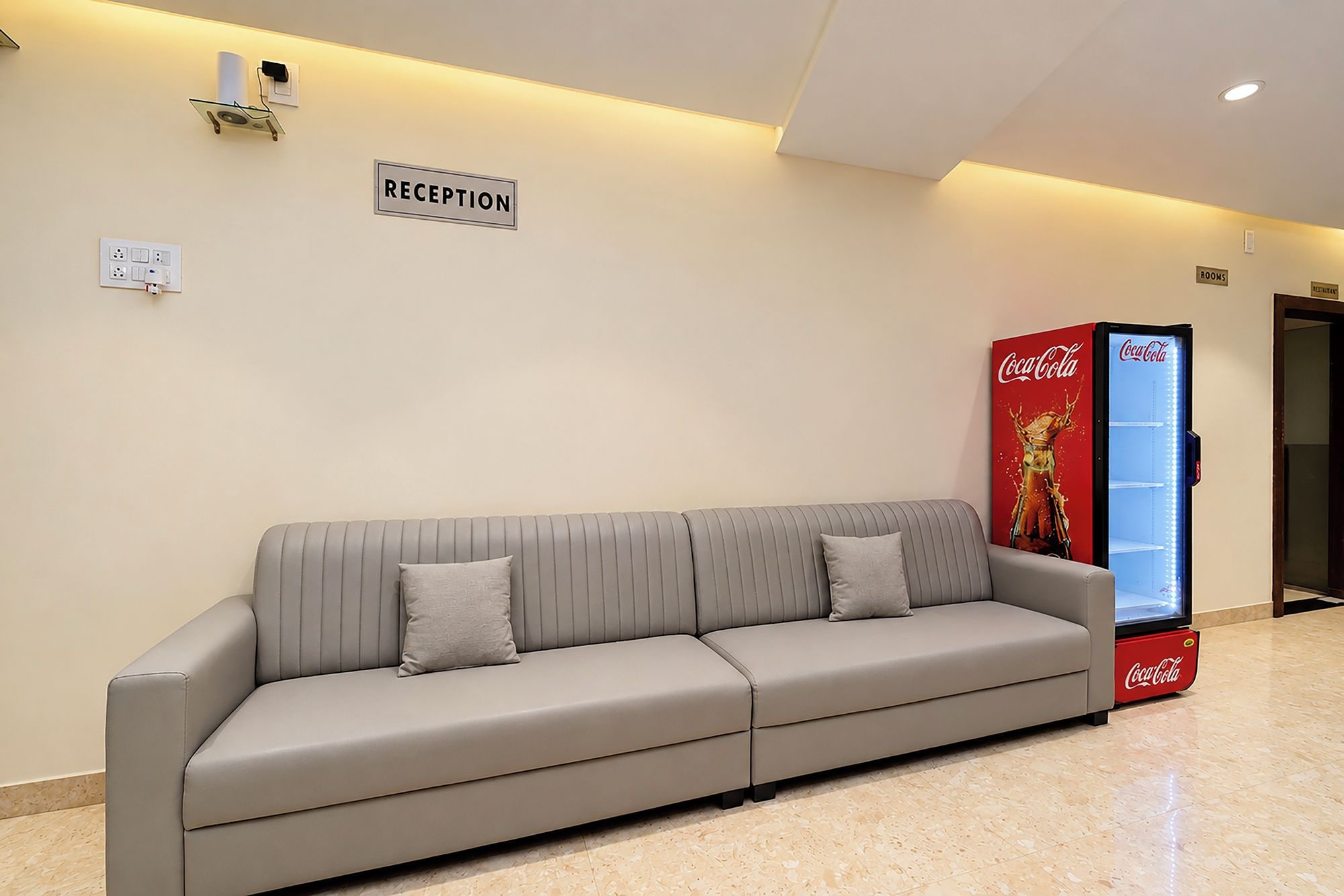 Ein Empfangsbereich mit einer Couch, einem Coca-Cola-Kühlschrank und einem Schild, das den Empfang anzeigt.