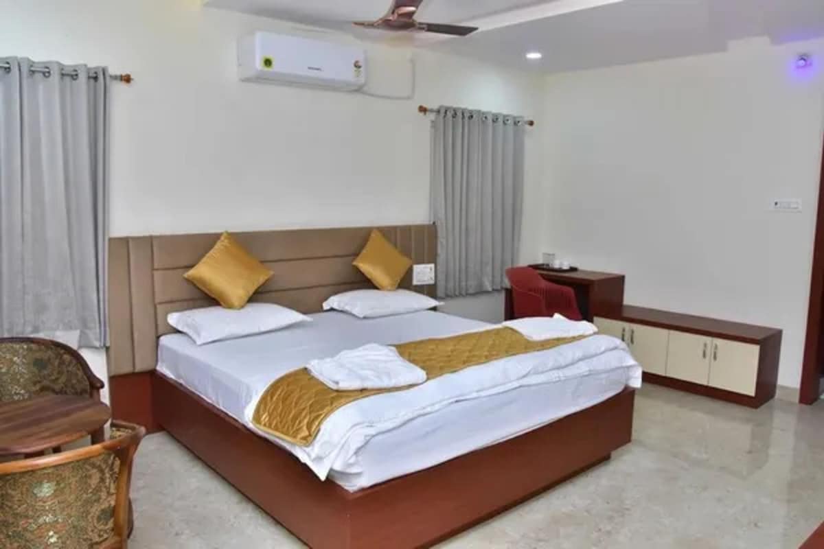 A hotel room with a large bed, a bedside table, a chair, and a wardrobe.