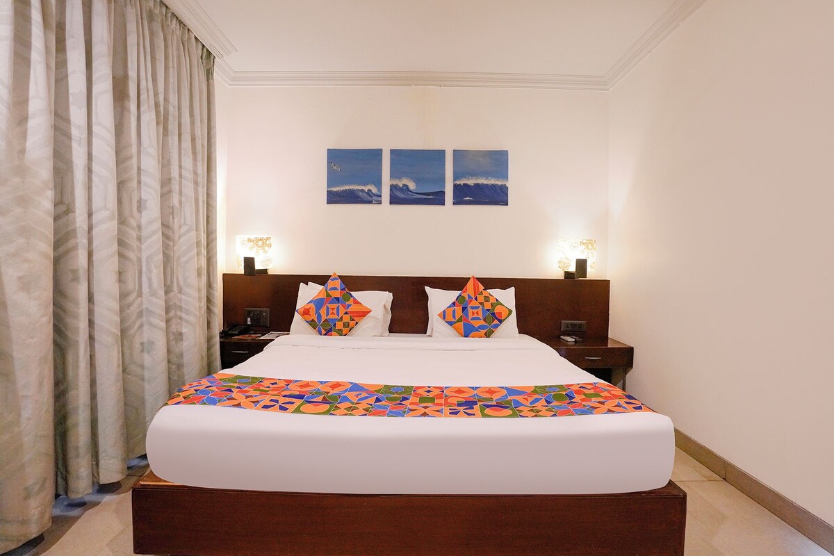 Habitación de hotel con una cama grande, dos lámparas fijadas a la pared y vistas al mar a través de la ventana.