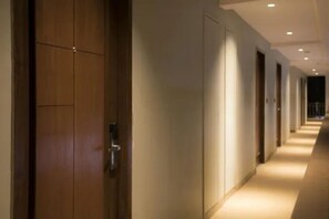 A hotel corridor with wooden doors and a carpeted floor.
