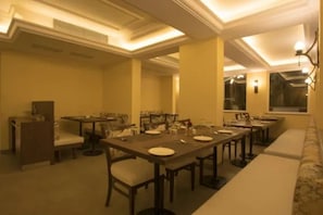 A dining area with multiple tables and chairs, a sofa, and a decorative wall.