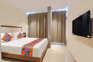 Una habitación de hotel con cama, cortinas, televisor y ventana.
