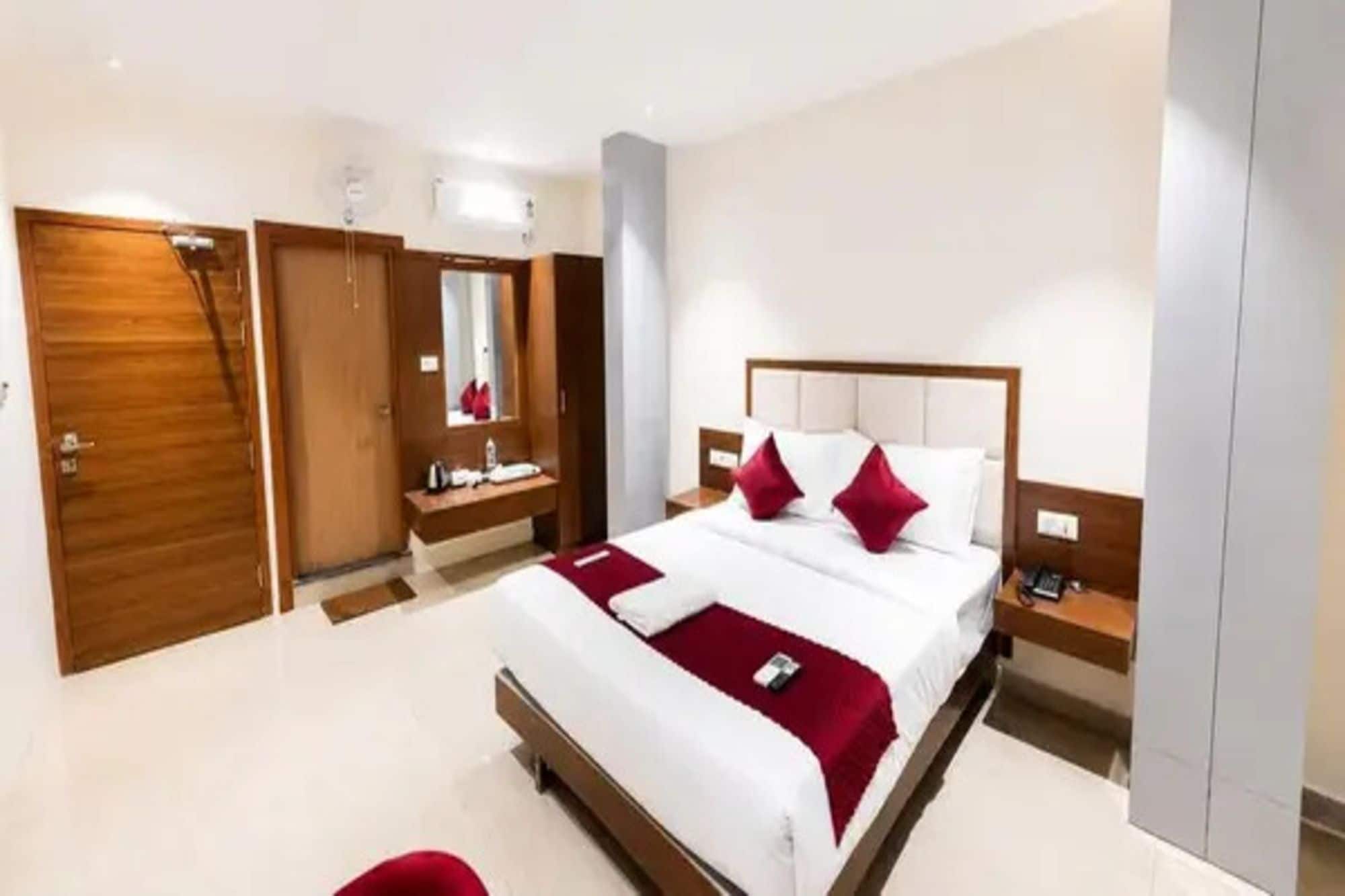 Una habitación de hotel con una cama grande, una mesita de noche, un armario y un espejo.