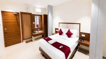 Una habitación de hotel con una cama grande, una mesita de noche, un armario y un espejo.