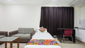 Una habitación de hotel con una cama, un sofá, una mesita y una zona de kitchenette.
