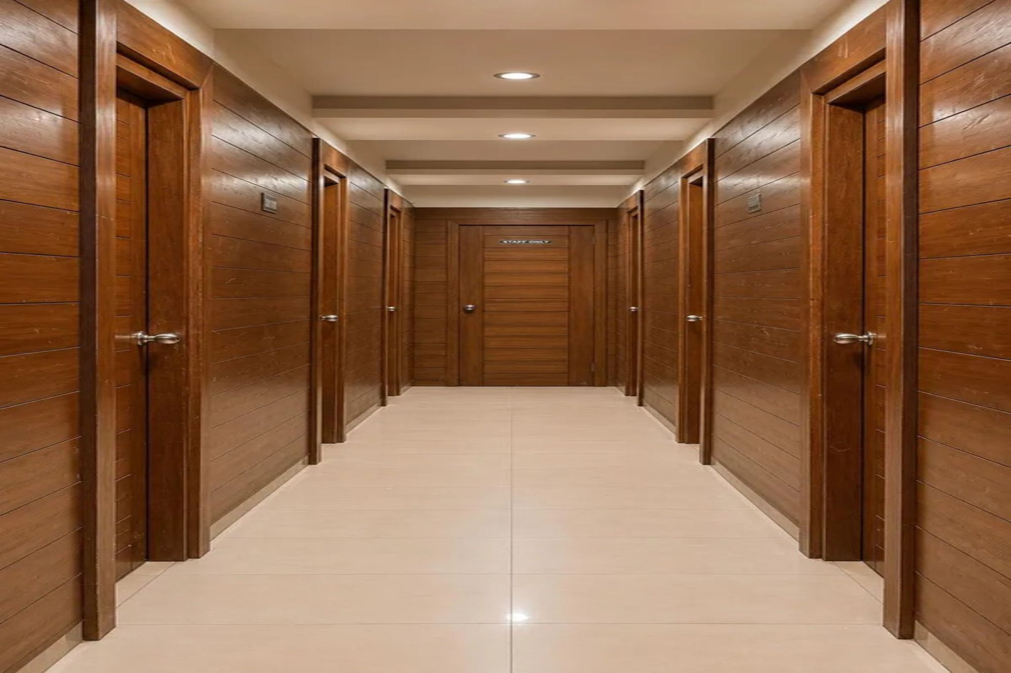 A corridor with wooden doors and a tiled floor.