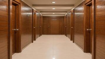 A corridor with wooden doors and a tiled floor.