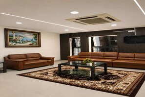 Uma sala de estar moderna com dois sofás de couro, uma mesa de centro de vidro e um tapete estampado.