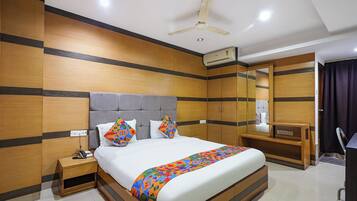 A hotel room with a bed, bedside table, nightstand, and a ceiling fan.