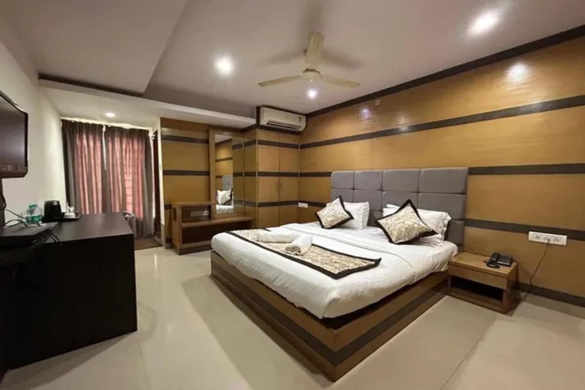 A hotel room with a large bed, bedside tables, a desk, and a ceiling fan.