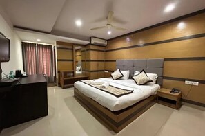 A hotel room with a large bed, bedside tables, a desk, and a ceiling fan. - Fabhotel Comfort Stay Inn (Bangalore)