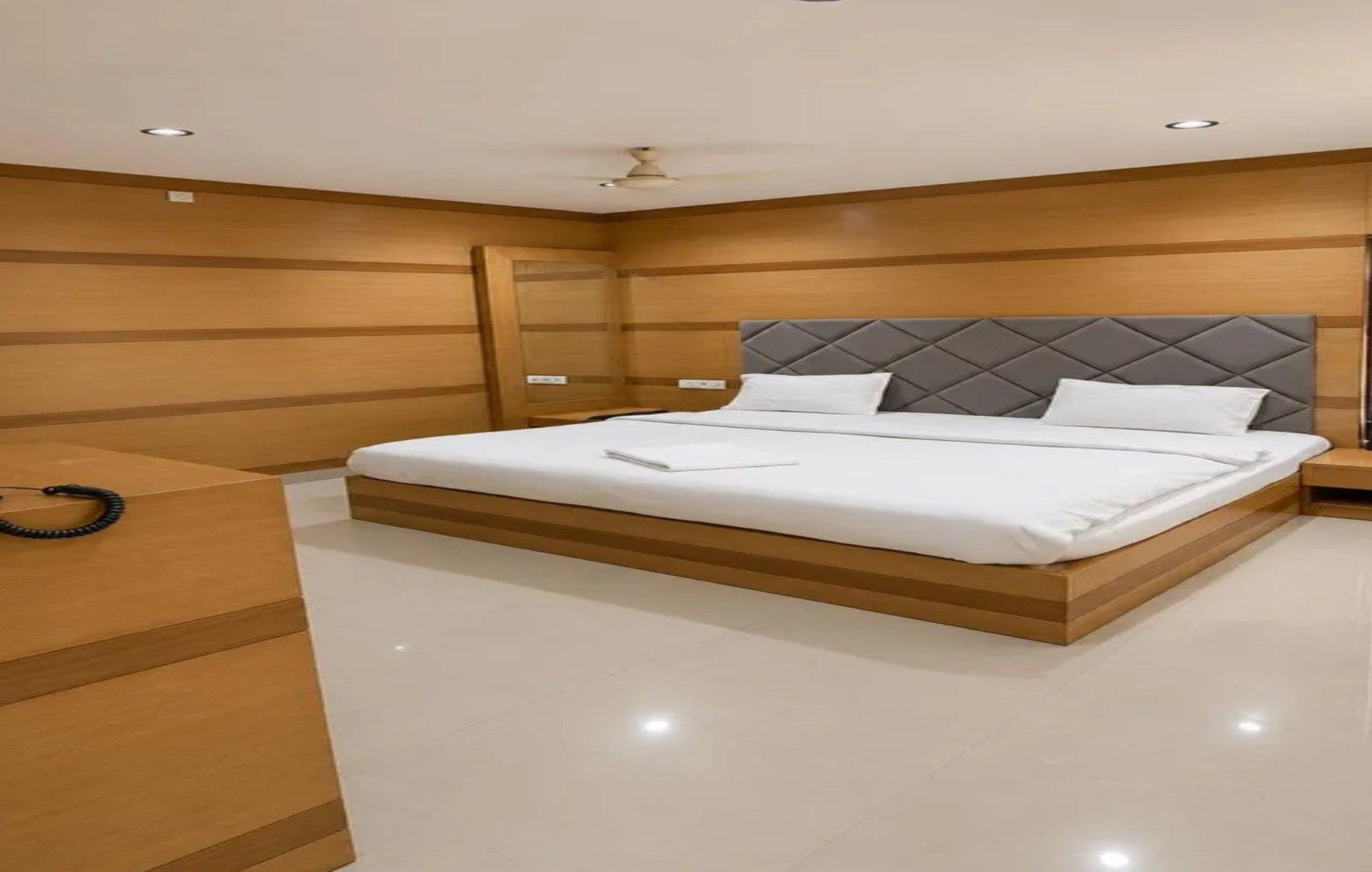Un dormitorio moderno con una cama grande, paneles de madera y un ventilador de techo.
