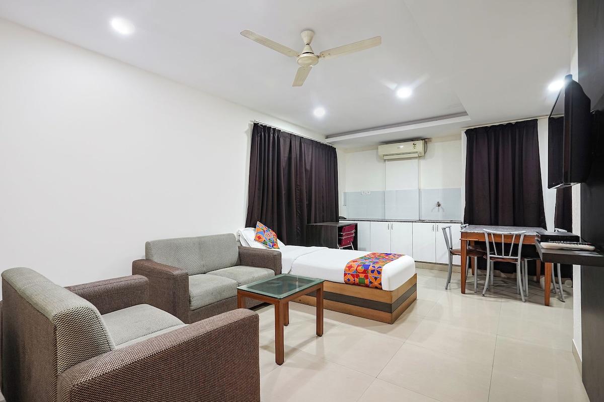 Habitación de hotel con cama, sofá, mesa de comedor y ventilador de techo.