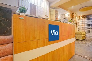 A reception desk with a 'Via' sign, a plant, and a check-out counter.