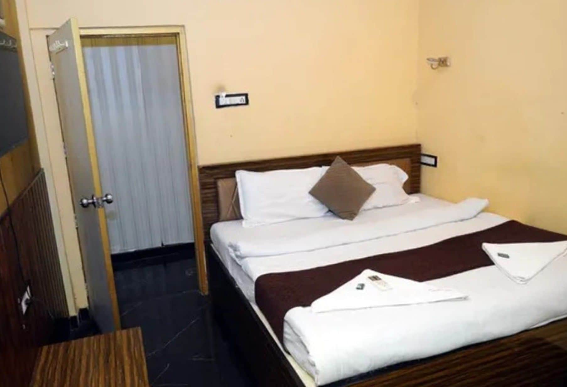 A hotel room with a bed, a door, and a wall-mounted sign.