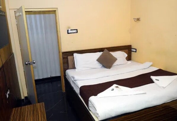 A hotel room with a bed, a door, and a wall-mounted sign.