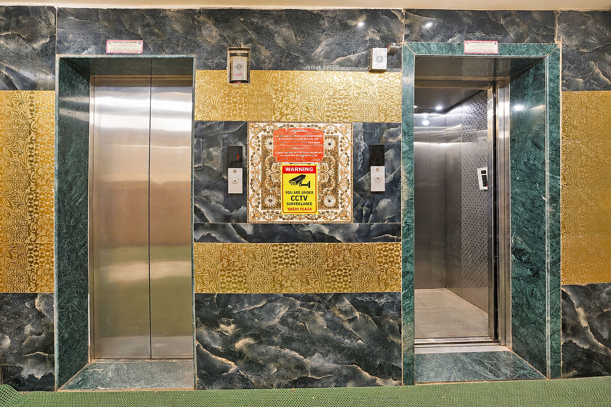 Un ascensor con un letrero de advertencia de circuito cerrado de televisión y una pared con diseño.