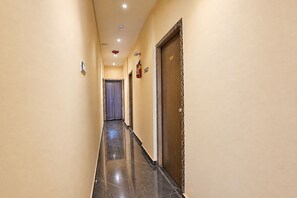 A corridor with a marble floor, a fire extinguisher, and a door with a decorative frame.