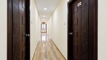 Un pasillo con dos puertas de madera oscura, cada una con una placa de número. El piso está cubierto de baldosas y las paredes están pintadas en un tono claro.