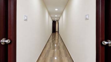 A hallway with a wooden floor and white walls, leading to a door at the end.