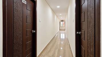 Un pasillo con dos puertas de madera, cada una con una placa de número, que conduce a una habitación con ventana.