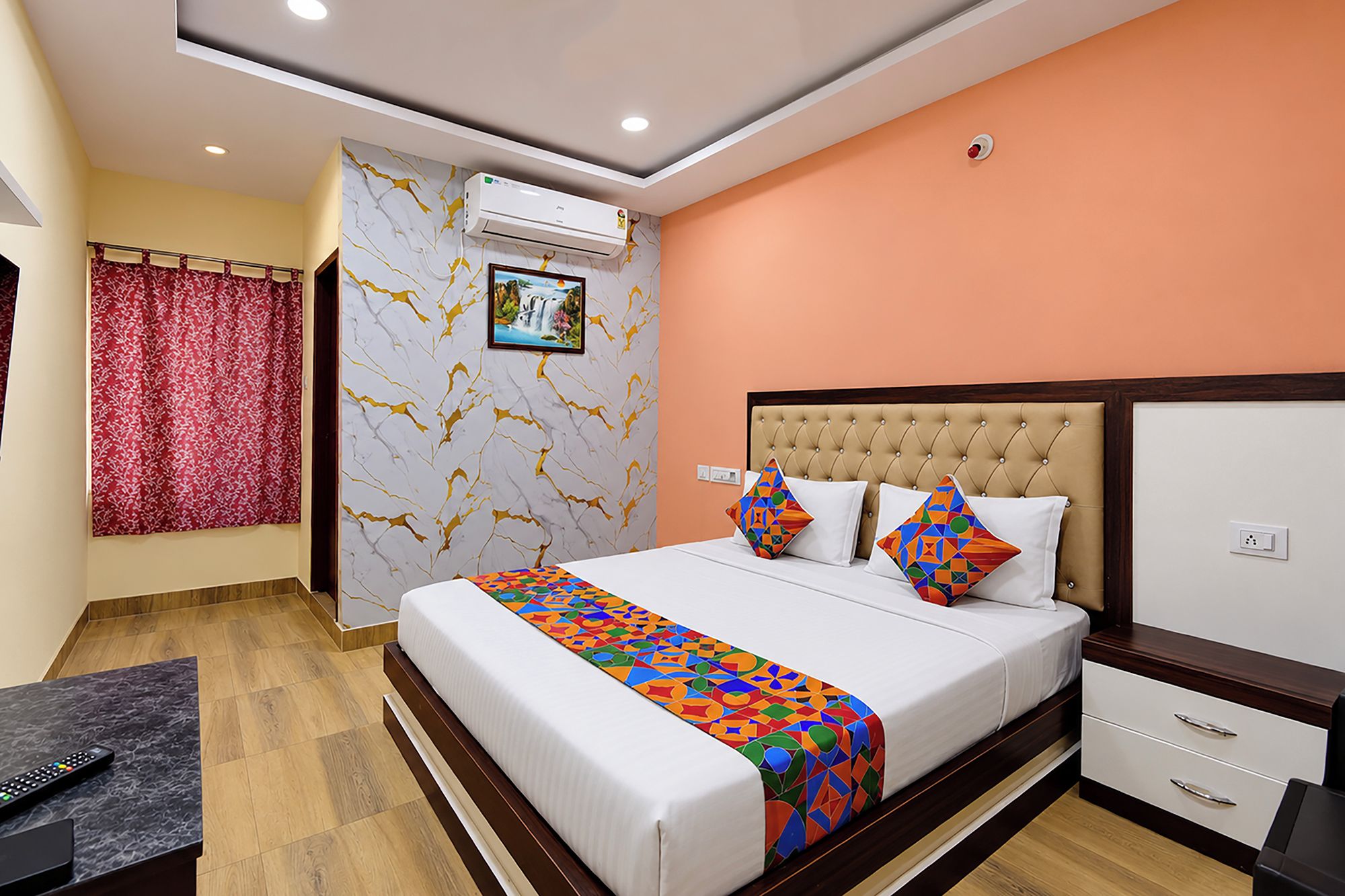 Habitación de hotel con cama, mesita de noche y aire acondicionado de pared.