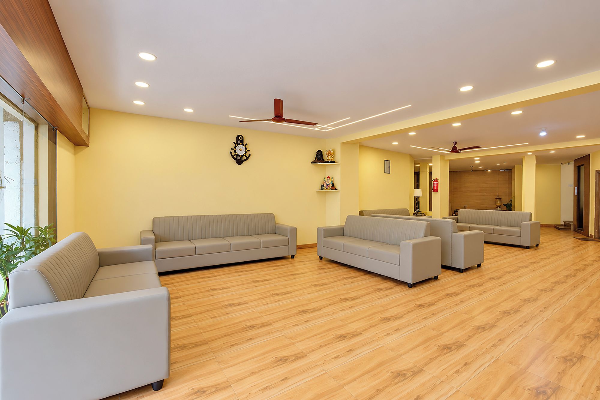 Amplia sala de estar con piso de madera, dos sofás, una mesa de centro y ventiladores de techo.