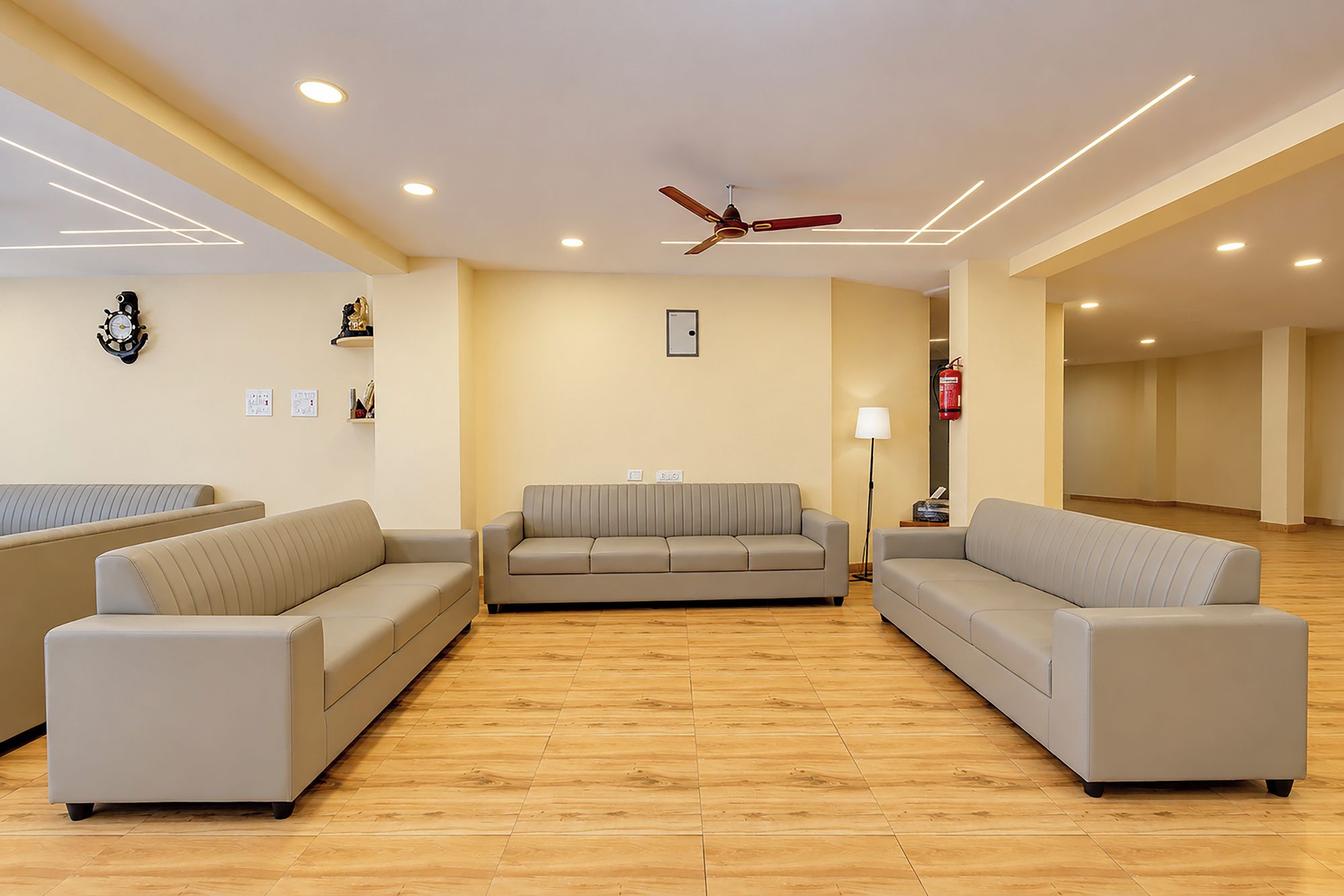 A modern living room with a beige sofa set, a ceiling fan, recessed lighting, and a wooden floor.
