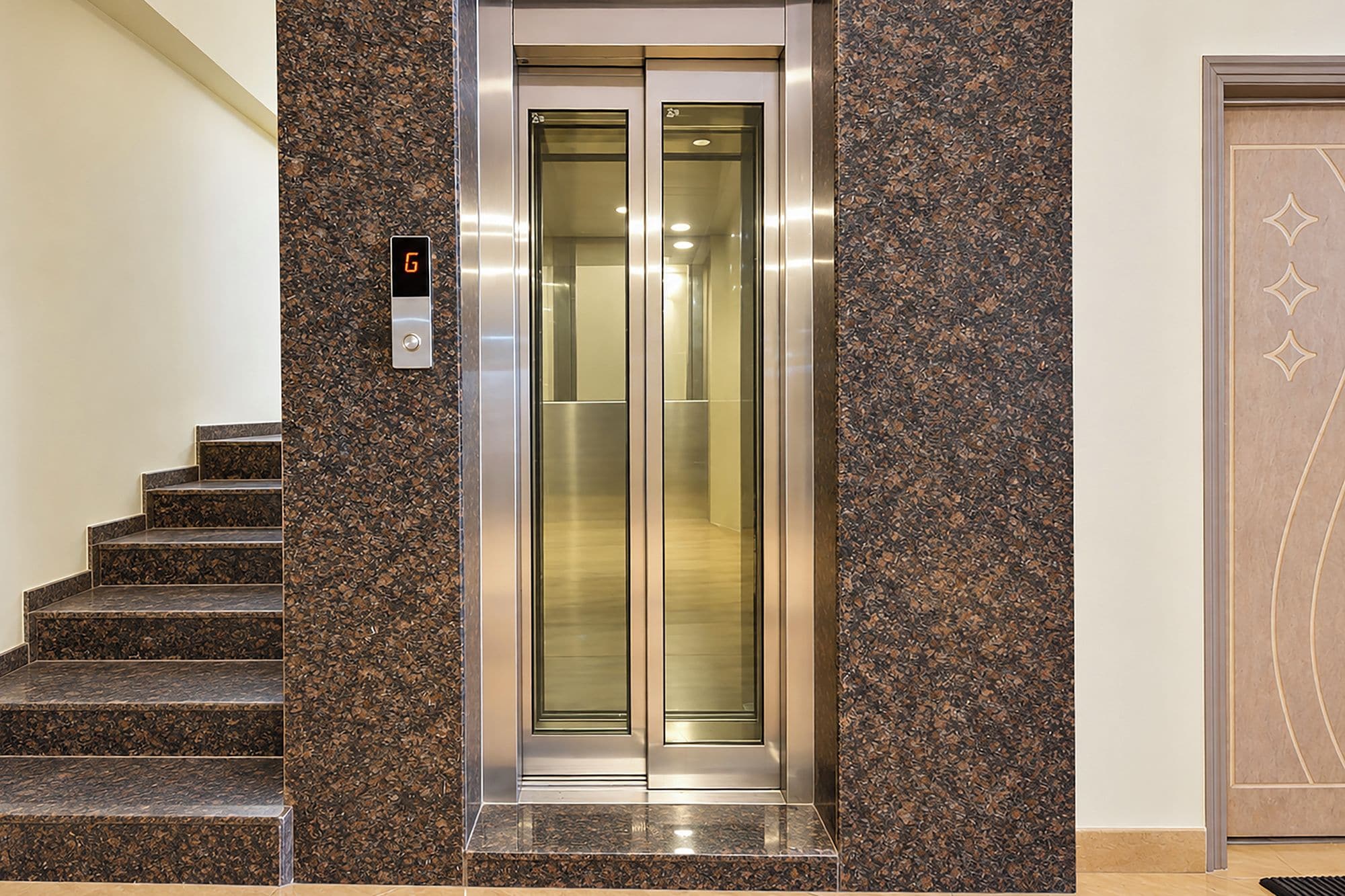 An elevator with a digital display, flanked by a staircase and a door with a geometric design.