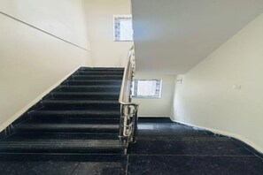 A staircase with a handrail, leading to a landing with a window. - Fabhotel Royal Elite Luxury (Hyderabad)