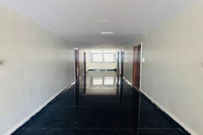A corridor with a shiny black floor, white walls, and a door at the end. - Fabhotel Royal Elite Luxury (Hyderabad)