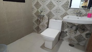 Un baño pequeño con inodoro, lavamanos y papel tapiz estampado.