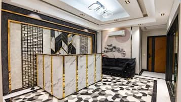 A modern reception area with a geometric patterned floor, a reception desk with a decorative screen, and a black sofa.