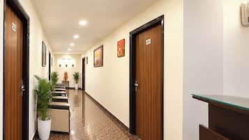 Pasillo de hotel con puertas de madera, con los números 204 y 203, y un mostrador de recepción con encimera de vidrio.