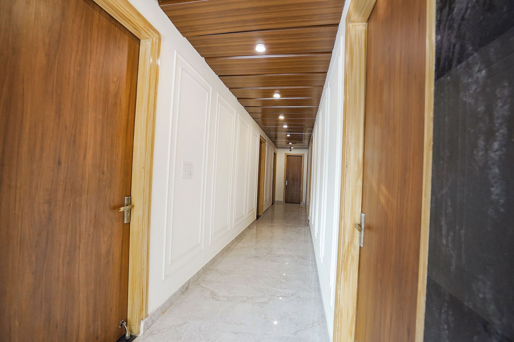 A hallway with wooden doors and a marble floor.