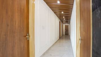 Un pasillo con puertas de madera y piso de mármol, que conduce a una habitación con techo de madera.