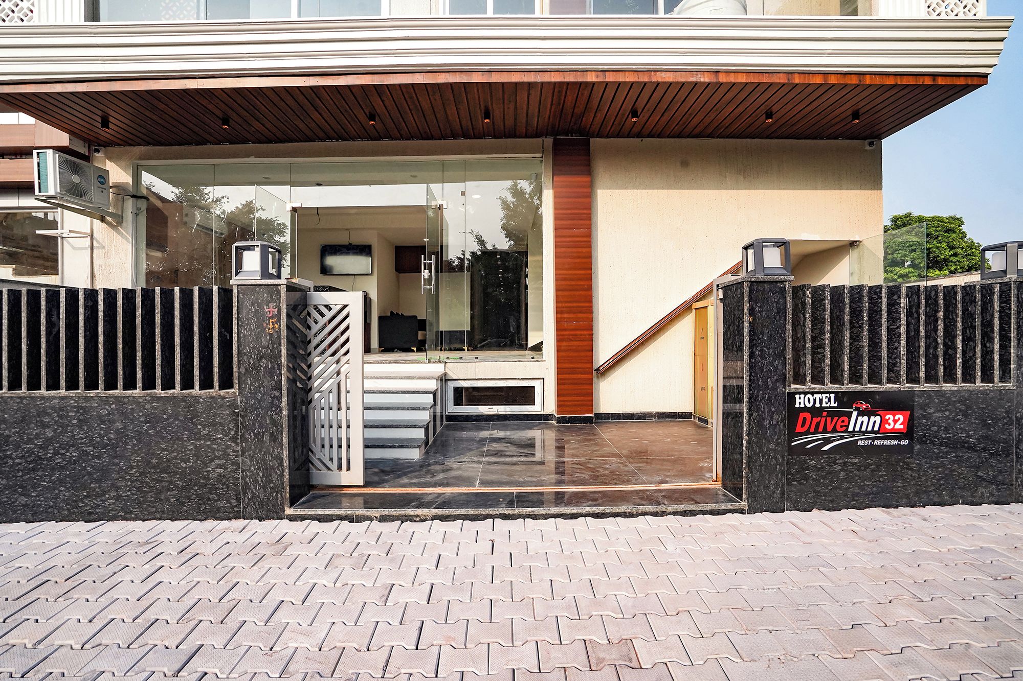Una entrada de hotel moderna con puerta de vidrio, escalera de madera y un letrero que dice Hotel Drive Inn 32.