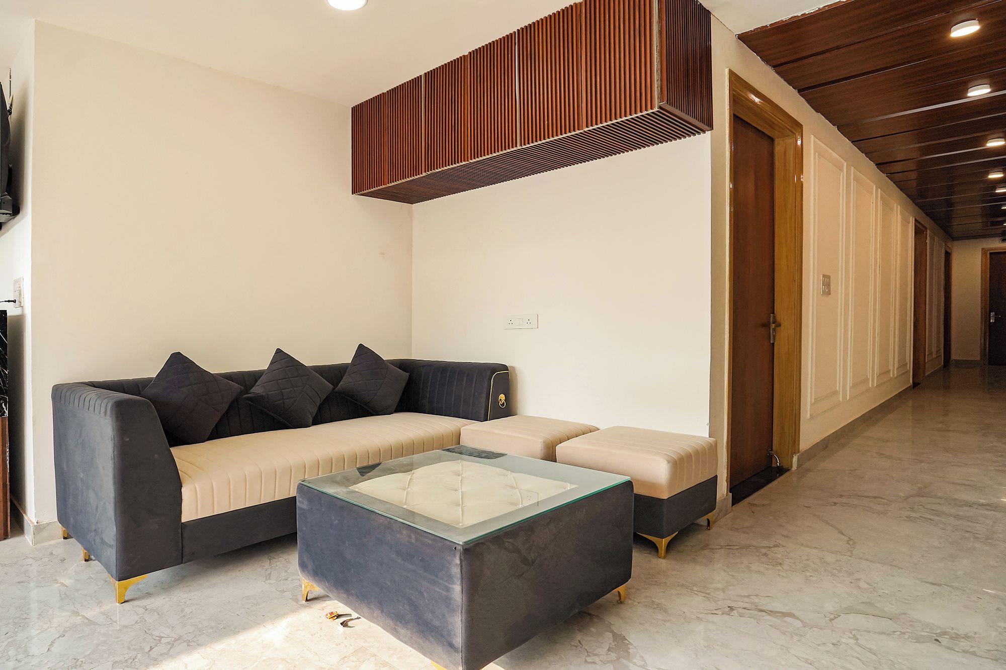 Una sala de estar moderna con un sofá modular, una mesa de centro de vidrio y un detalle de techo de madera.