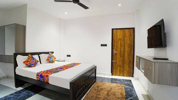 Un dormitorio moderno con una cama, un ventilador de techo, un televisor y una puerta de madera.