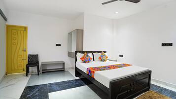 A modern bedroom with a bed, a ceiling fan, a small table, and a yellow door.