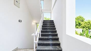 Una escalera con barandilla blanca que lleva a un rellano con ventanal.