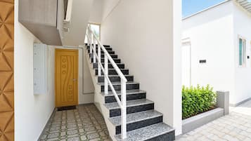 A staircase with a white handrail leading to a door with a geometric design.