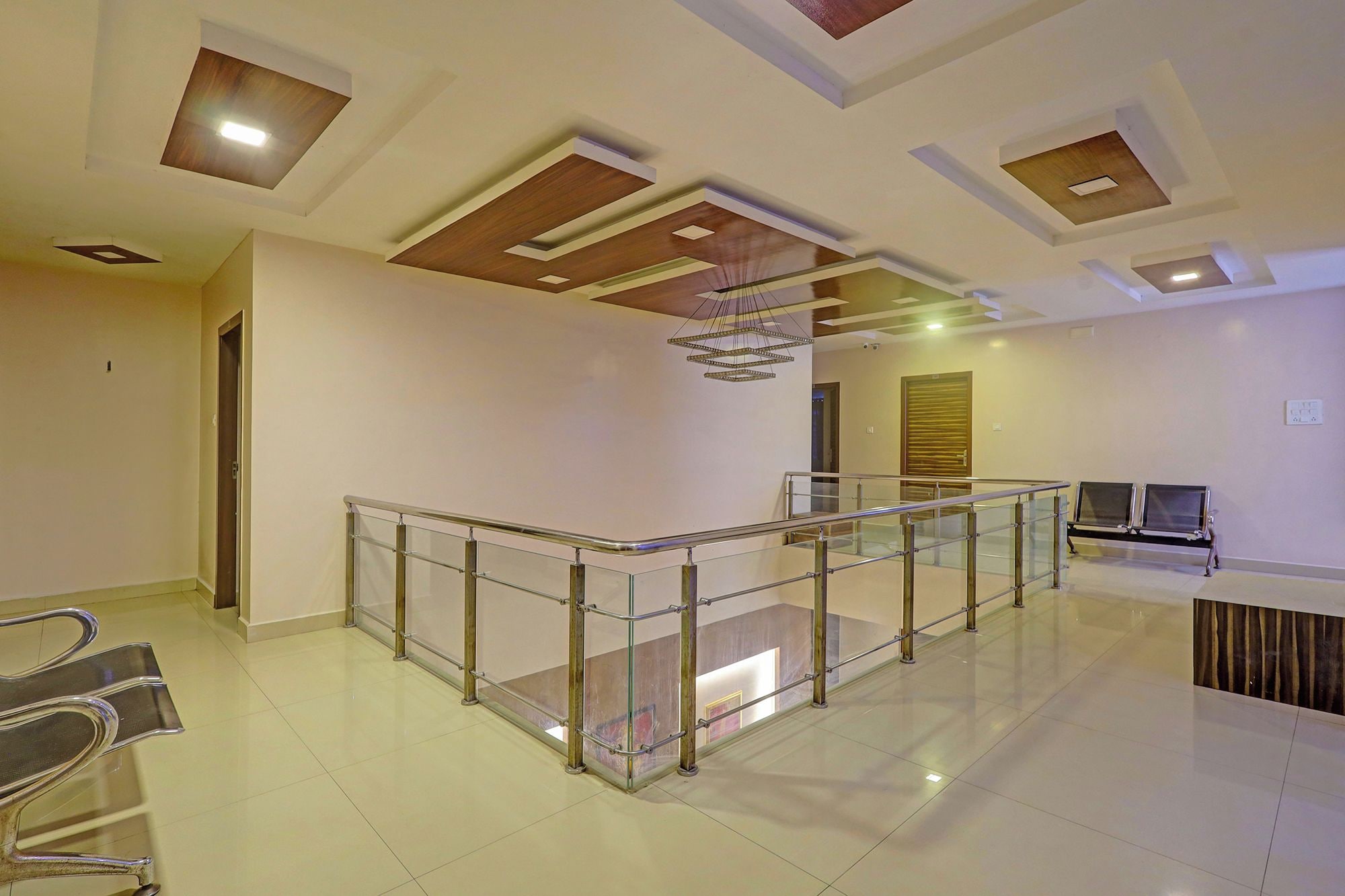 A spacious interior with a glass railing staircase, a reception desk, and a modern ceiling design.