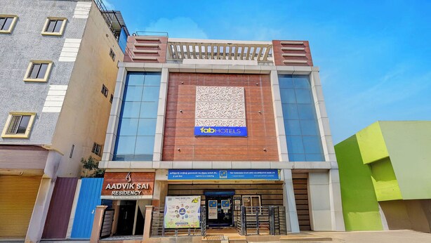 Um edifício de vários andares com uma placa chamativa da 'fab hotels' na fachada.