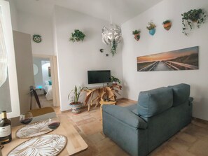 En stue med sofa, fjernsyn, sofabord i træ og en potteplante.