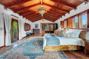 A spacious room with a high wooden ceiling, a large bed with multiple pillows, a patterned rug, and a view through a window. - Villa Brisas in Coral Gables area (Miami)