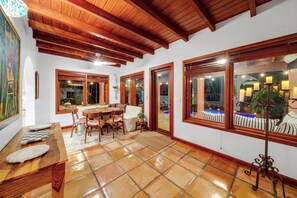 A room with a wooden ceiling, tiled floor, a dining table with chairs, and large windows with curtains. - Villa Brisas in Coral Gables area (Miami)