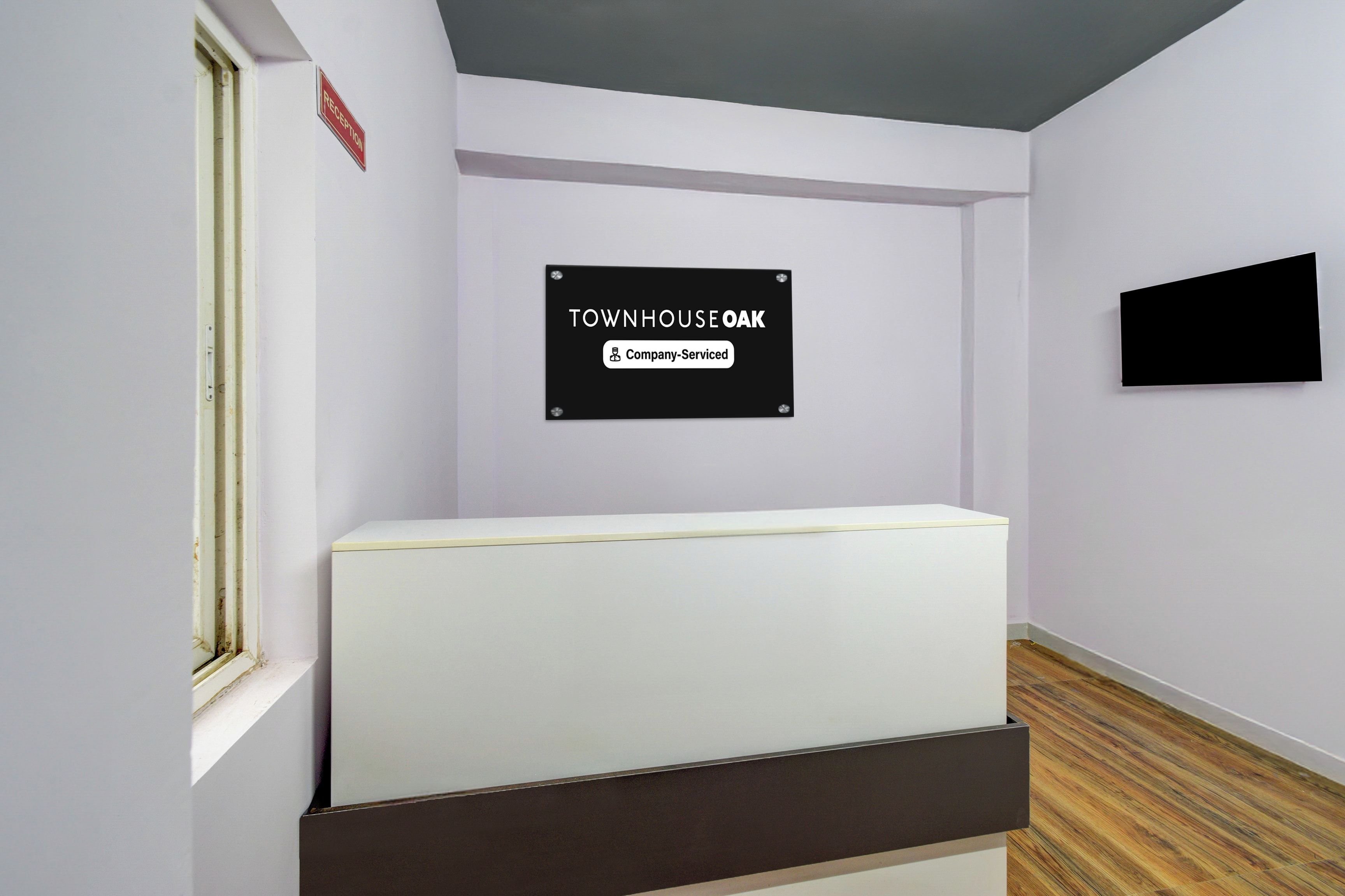 Un espace d’accueil avec une enseigne indiquant « TOWNHOUSE OAK » et une étiquette indiquant « Service assuré par l’entreprise ».